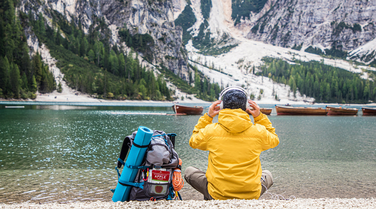 Backpacker sitting by a lake with Nature's Turn Fruit Crisps in their pack